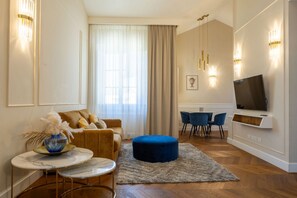 Ein modernes Wohnzimmer mit einer Couch, Hocker und einem an der Wand befestigten Fernseher.