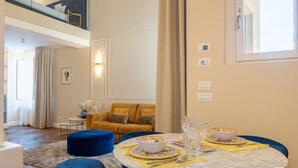 A modern living room with a round marble table, blue chairs, and a sofa with yellow cushions. - Calzaiuoli Gold Private House with Terrace (Firenze)