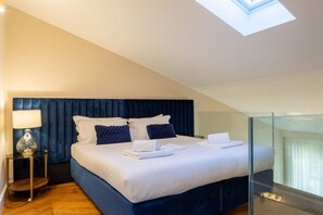 Ein modernes Hotelzimmer mit einem großen Bett, einer Glasabtrennung, einem Oberlicht und einem Nachttisch mit Lampe.