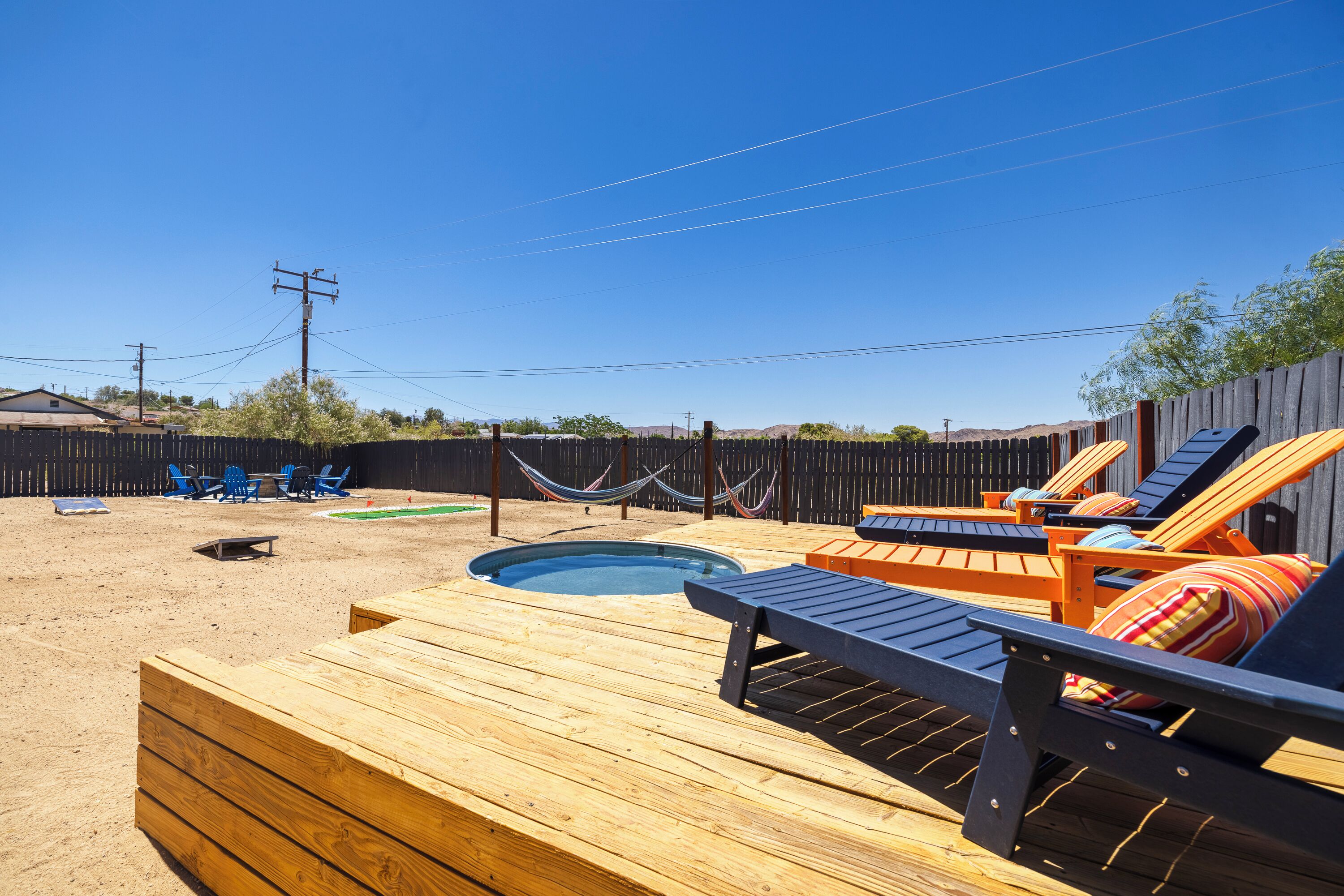A wooden deck with lounge chairs and a small pool.
