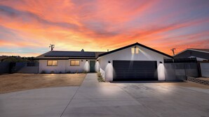 A modern two-story house with a garage, solar panels, and a well-maintained driveway.
