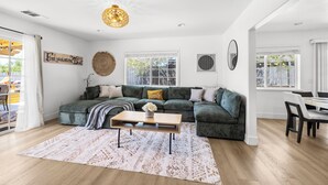 A spacious living room with a sectional sofa, a coffee table, and a dining area with a table and chairs.