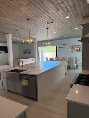 A modern kitchen with a central island, stainless steel appliances, and pendant lighting.