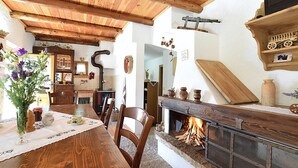 A wooden dining table with chairs, a fireplace, and a wooden ceiling. - Baita Costa di Gial (Lamon)