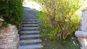 A stone staircase leading up a hill, surrounded by greenery and a wooden fence. - Baita Costa di Gial (Lamon)
