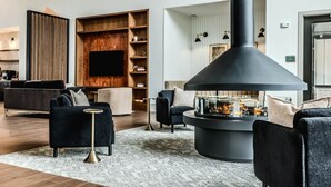 A modern living room with a fireplace, sofas, and a TV mounted on a wooden wall.