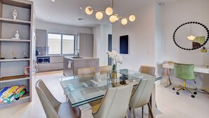 A modern kitchen with a central island, a dining area with a glass table, and a workspace with a desk and chair. - Modern condo, steps to beach. Gym, generator, gated community. (Nassau)
