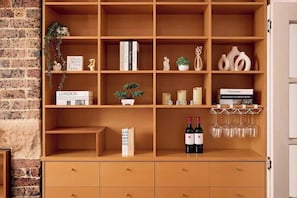 Une bibliothèque en bois, avec des livres, des objets de décoration et des bouteilles de vin.