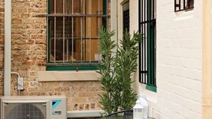 Un patio con una mesa, sillas, una planta en maceta y un equipo de aire acondicionado.