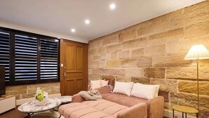 Un salón acogedor con pared de piedra, un sofá, una mesa de centro y una lámpara.