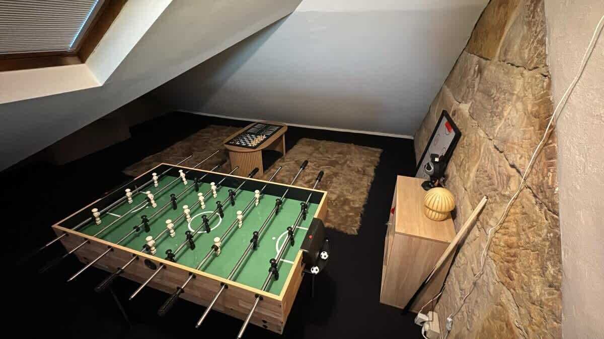 Une pièce comprenant une table de baby-foot, une petite table avec un jeu de société et un appareil fixé au mur.