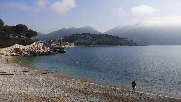 A coastal scene with a pebbled beach, a lighthouse, and a mountainous backdrop. - BEAUTIFUL HOUSE IN PROVENCE (Avignon)