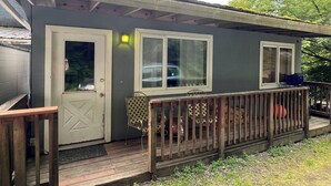 En liten, envåningsbyggnad med en veranda, en dörr och två fönster.