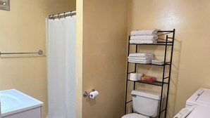 Une salle de bain comprenant des toilettes, une étagère avec des serviettes, un rideau de douche et un lavabo.