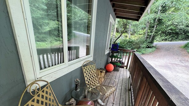 Une terrasse en bois dotée d’une rambarde, d’un banc et d’une table avec un plateau en verre.