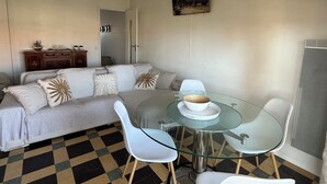 A dining area with a glass table, white chairs, and a checkered floor.