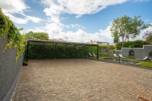 A covered outdoor area with a cobblestone floor, a pergola, and a poolside with lounge chairs. - Studio Apartment '1' with Shared Pool, Shared Garden and Wi-Fi (Funchal)