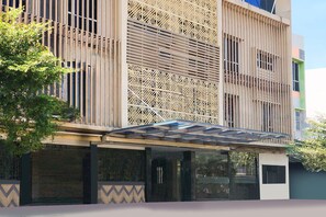 A modern building with a patterned facade, large windows, and a covered entrance area.