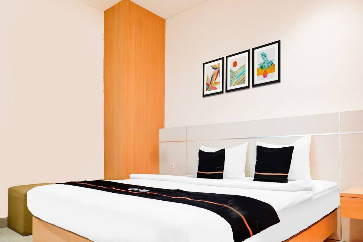 Une chambre d’hôtel avec un lit, une table de chevet, un mur décoratif en bois et trois œuvres d’art encadrées accrochées au mur.