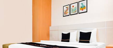 Une chambre d’hôtel avec un lit, une table de chevet, un mur décoratif en bois et trois œuvres d’art encadrées accrochées au mur.