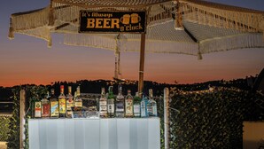 A bar with a sign that reads "It's Always Beer o'Clock" and a variety of liquor bottles.