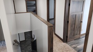 Un intérieur moderne avec un escalier, une porte en bois et un couloir menant à une autre pièce.
