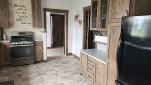 Une cuisine avec des meubles en bois, une cuisinière en acier inoxydable et un réfrigérateur noir.