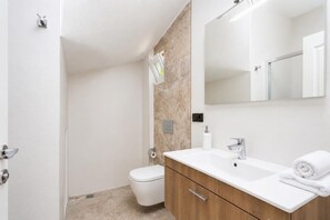 A modern bathroom with a toilet, sink, and mirror.
