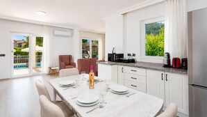 A modern kitchen with a dining area, a view of greenery, and a pool outside. - Daisy Villa - Five Bedroom Villa, Sleeps 10 (Dalyan)