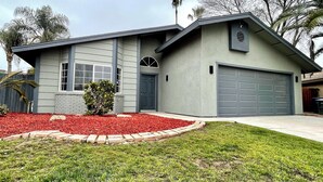 A modern two-story house with a garage, a small front yard with red mulch, and a well-maintained lawn. - Relaxed Cozy Pool House (Bakersfield)