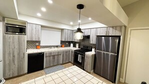 A modern kitchen with grey cabinetry, a stainless steel refrigerator, a built-in microwave, and a gas stove. - Relaxed Cozy Pool House (Bakersfield)