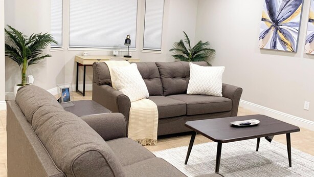 A living room with a sectional sofa, a coffee table, and two potted plants. - Relaxed Cozy Pool House (Bakersfield)