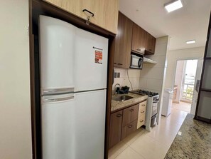 Una cocina con refrigerador, microondas, estufa y pileta.