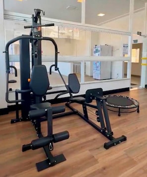 Une salle de sport équipée de matériel d’exercice, d’un miroir et d’un trampoline.