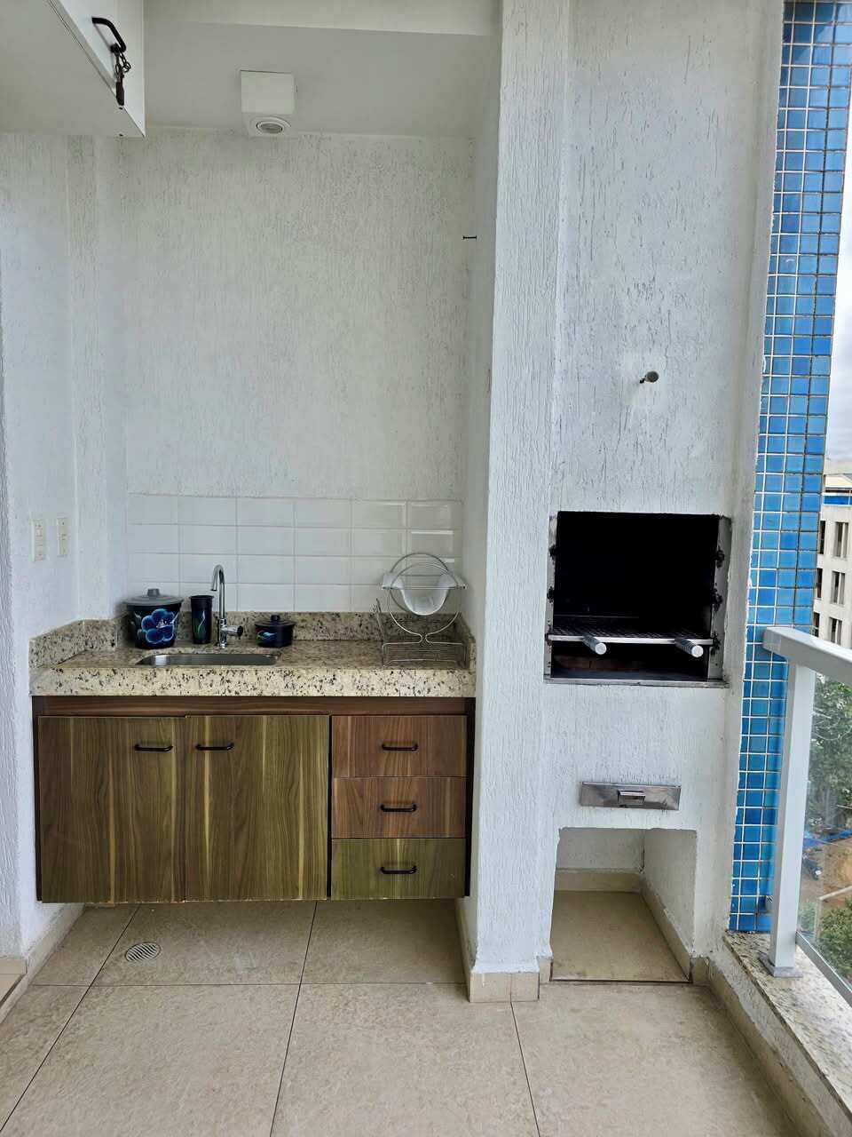 Een kleine keuken met een spoelbak, aanrecht en houten keukenkastjes.
