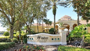A sign for Windsor Hills Clubhouse surrounded by lush greenery and palm trees.