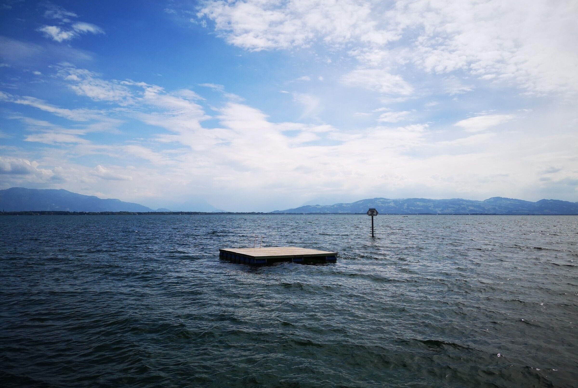 A calm body of water with a floating platform and a buoy.