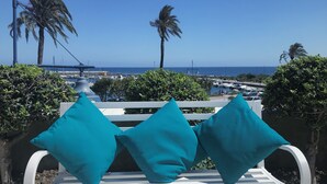 A white bench with teal cushions, overlooking a marina with boats and palm trees, under a clear blue sky. - Apartment 'Modern Marina Apt Fantastic' with Sea View, Wi-Fi and Air Conditioning (Estepona)