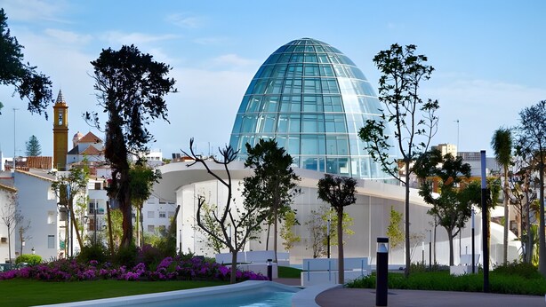 A modern building with a glass dome, surrounded by a landscaped pool area with trees and shrubs. - Apartment 'Modern Marina Apt Fantastic' with Sea View, Wi-Fi and Air Conditioning (Estepona)