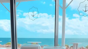 Two wine glasses on a table with a view of the sea and a white structure in the background. - Apartment 'Modern Marina Apt Fantastic' with Sea View, Wi-Fi and Air Conditioning (Estepona)