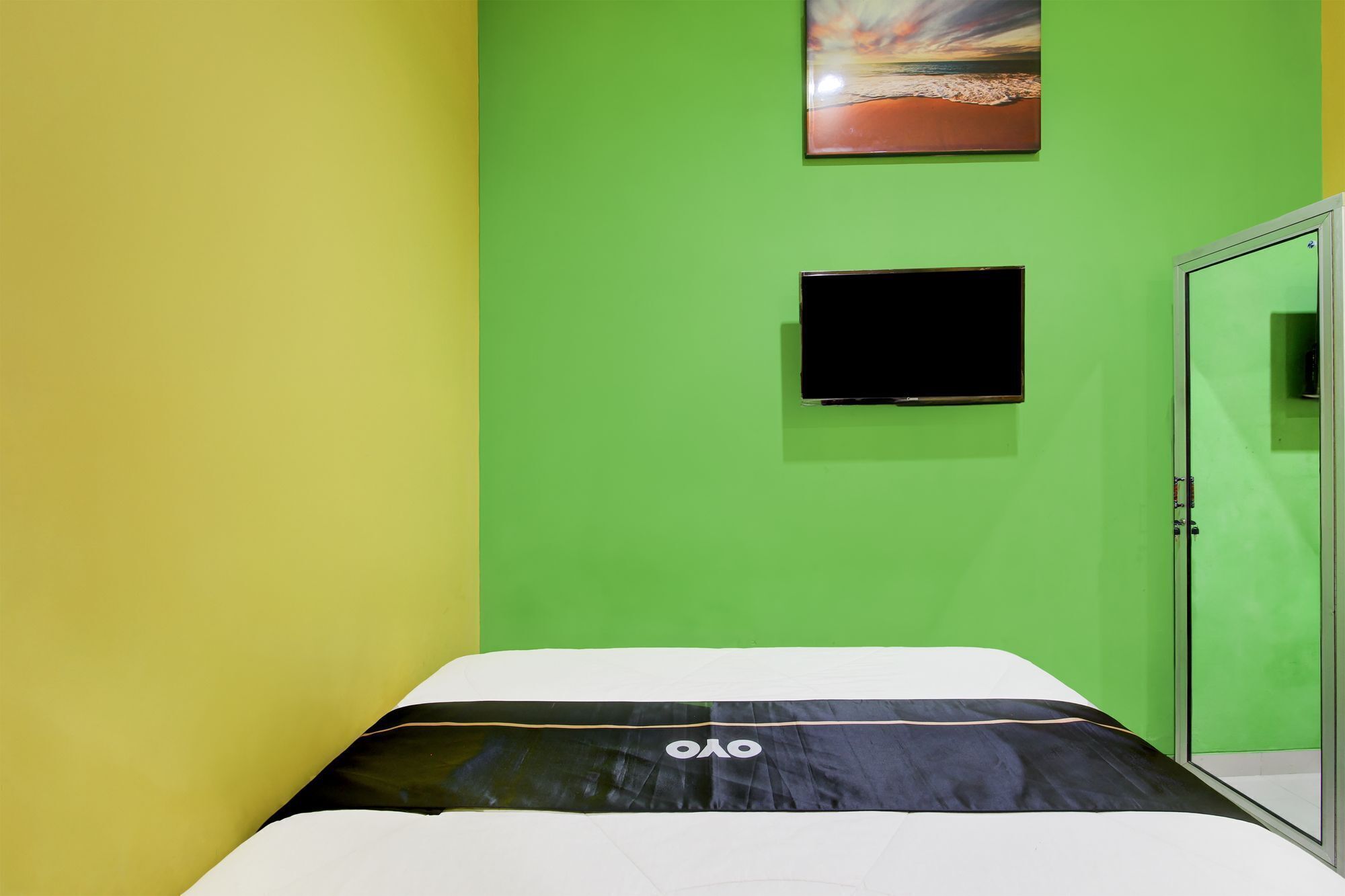 Ein Zimmer mit einem Bett, einem an der Wand befestigten Fernseher und einer Tür.