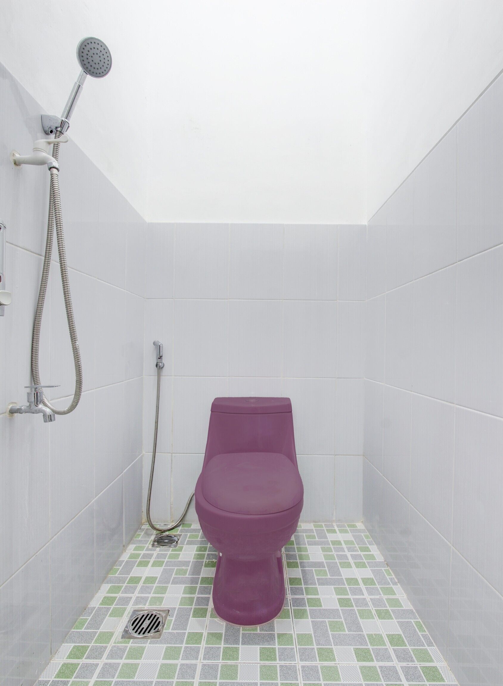 A small, private bathroom with a purple toilet, a showerhead, and a tiled floor.