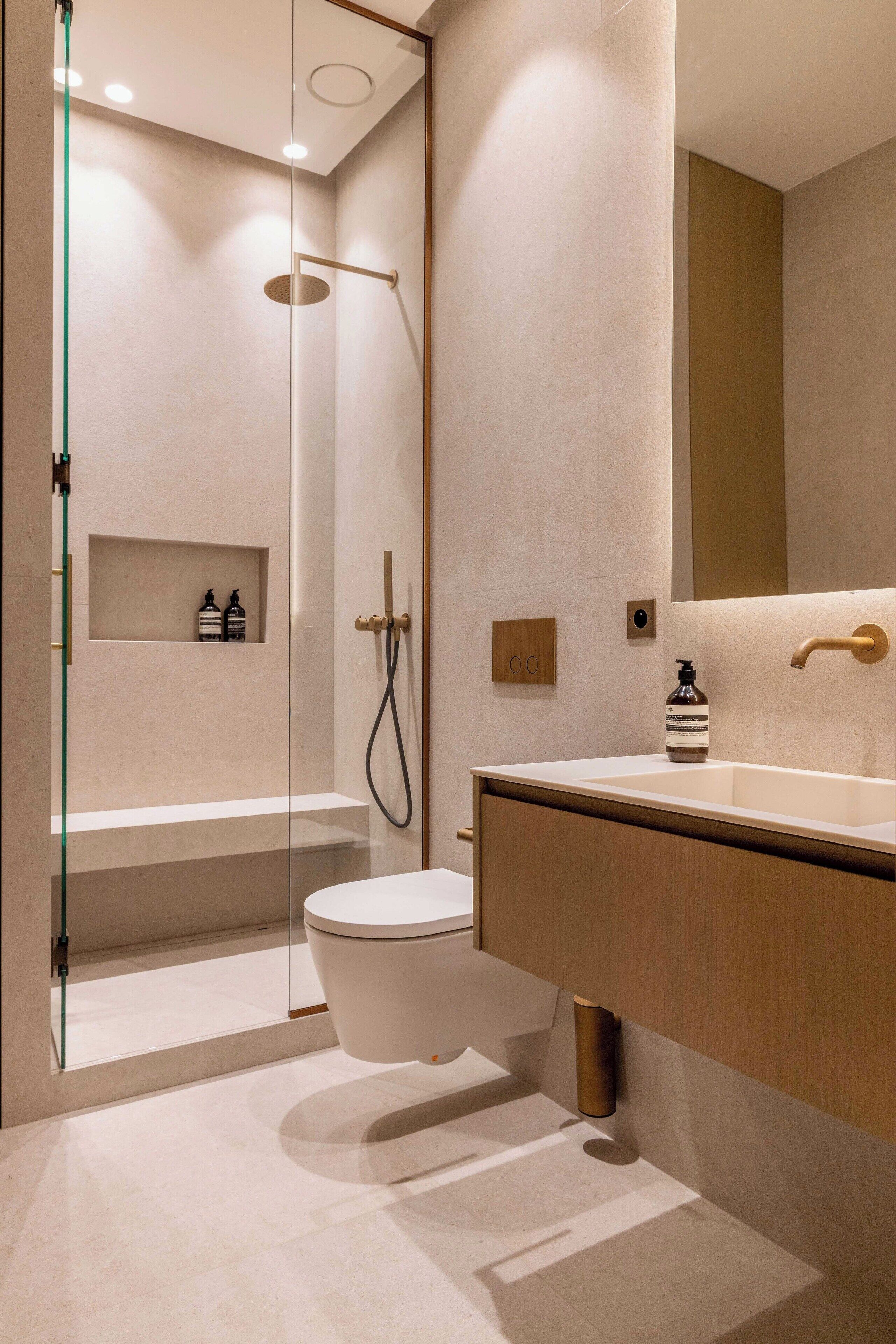 A modern bathroom with a glass-enclosed shower, a white toilet, and a wooden vanity with a mirror.