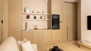 Une cuisine moderne avec des meubles en bois, un four encastré et un four à micro-ondes. On y trouve un plan de travail avec un évier et un grille-pain.