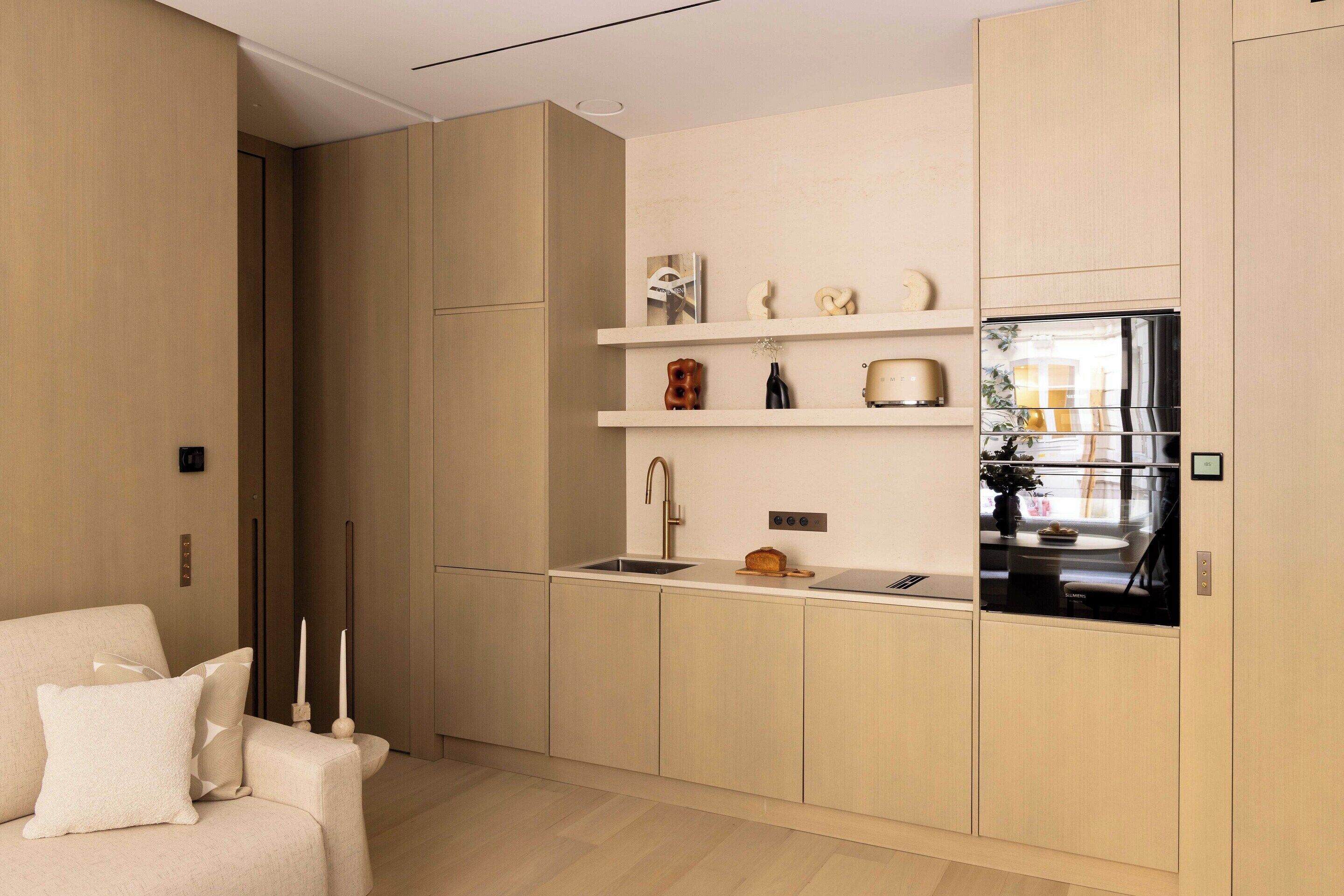 Eine moderne Küche mit hellen Holzschränken, einer eingebauten Spüle und einem Kühlschrank.