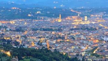 Une vue panoramique d’une ville au crépuscule, avec des bâtiments illuminés et une architecture historique remarquable.