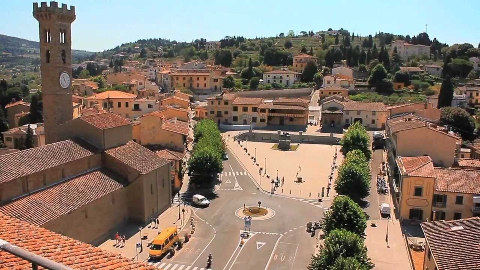A town square with buildings, a clock tower, and a roundabout.