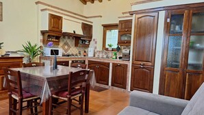 A kitchen with wooden cabinets, a dining table with chairs, and a grey sofa in a living area. - Tuscan Barn 15 min from Florence, Parking, Garden (Pian di Mugnone)