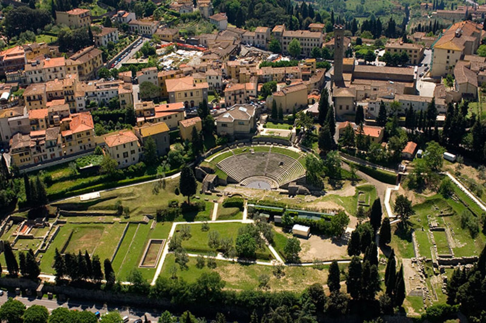 Vue aérienne d’une ville historique, avec un amphithéâtre central entouré de bâtiments résidentiels et d’espaces verts.