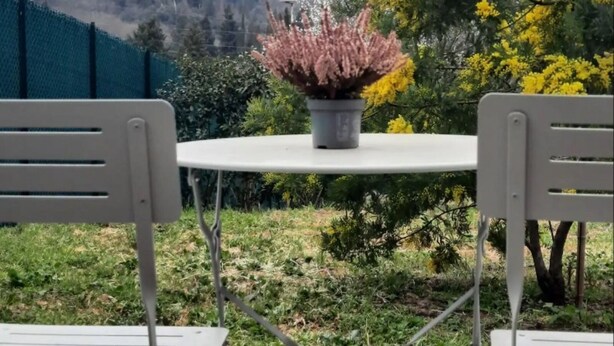 A view from a balcony with two white metal chairs and a table, overlooking a hillside with buildings and trees. - Tuscan Barn 15 min from Florence, Parking, Garden (Pian di Mugnone)